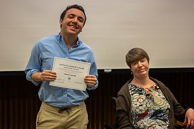 Student Dominic Limaldi holding the First Year Student Award, standing 下一个 to Professor Katie Roquemore.